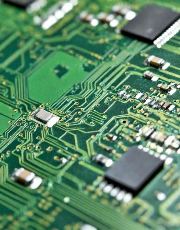 Detailansicht einer grünen Leiterplatte mit verschiedenen elektronischen Bauteilen.